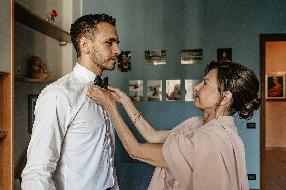 Matrimonio a Torino. Preparazione dello sposo. Sposo con la mamma che gli sistema il papillon.