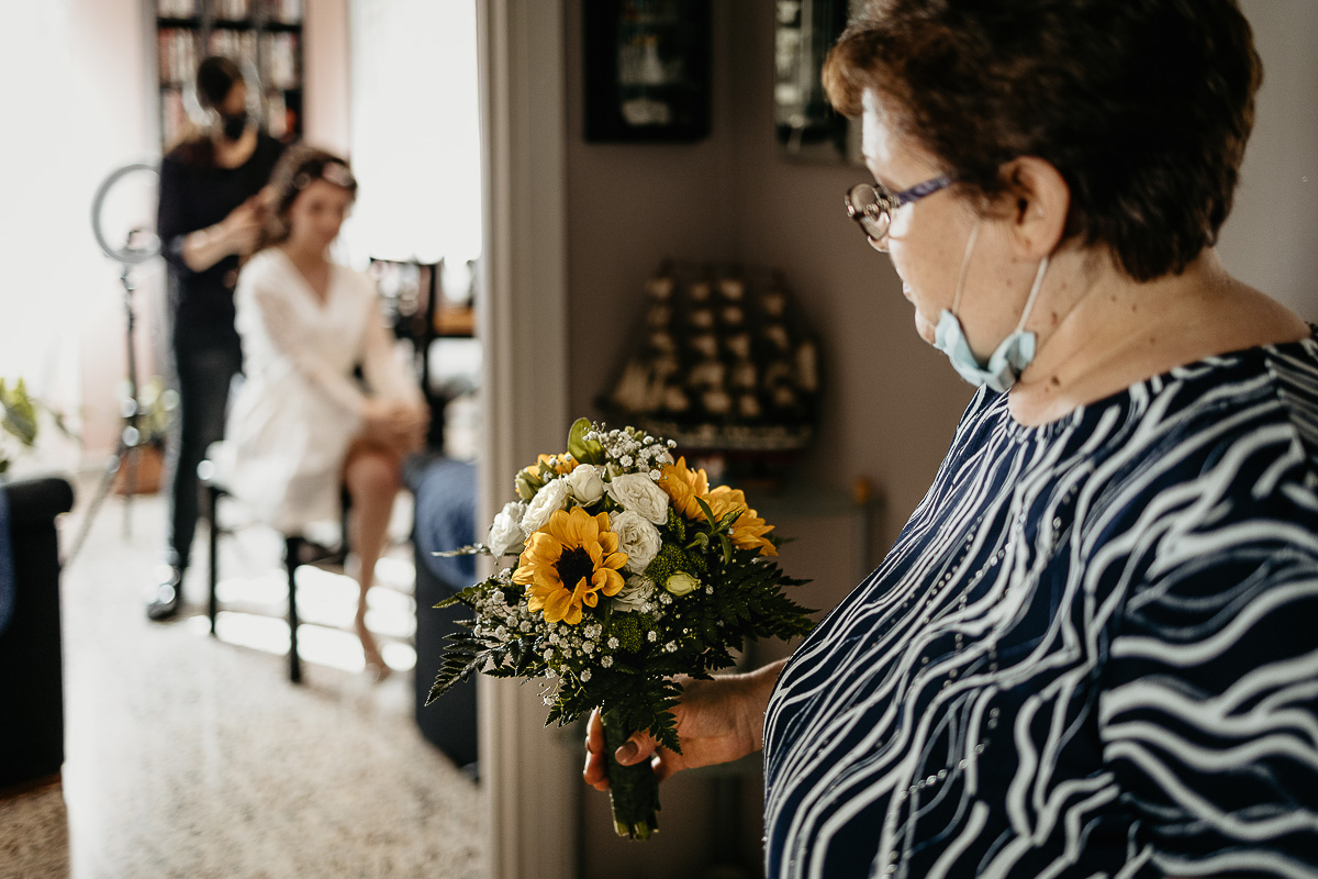 Matrimonio a Torino. Preparazione della sposa mamma che guarda la sposa da una porta con in mano il bouquet di girasoli