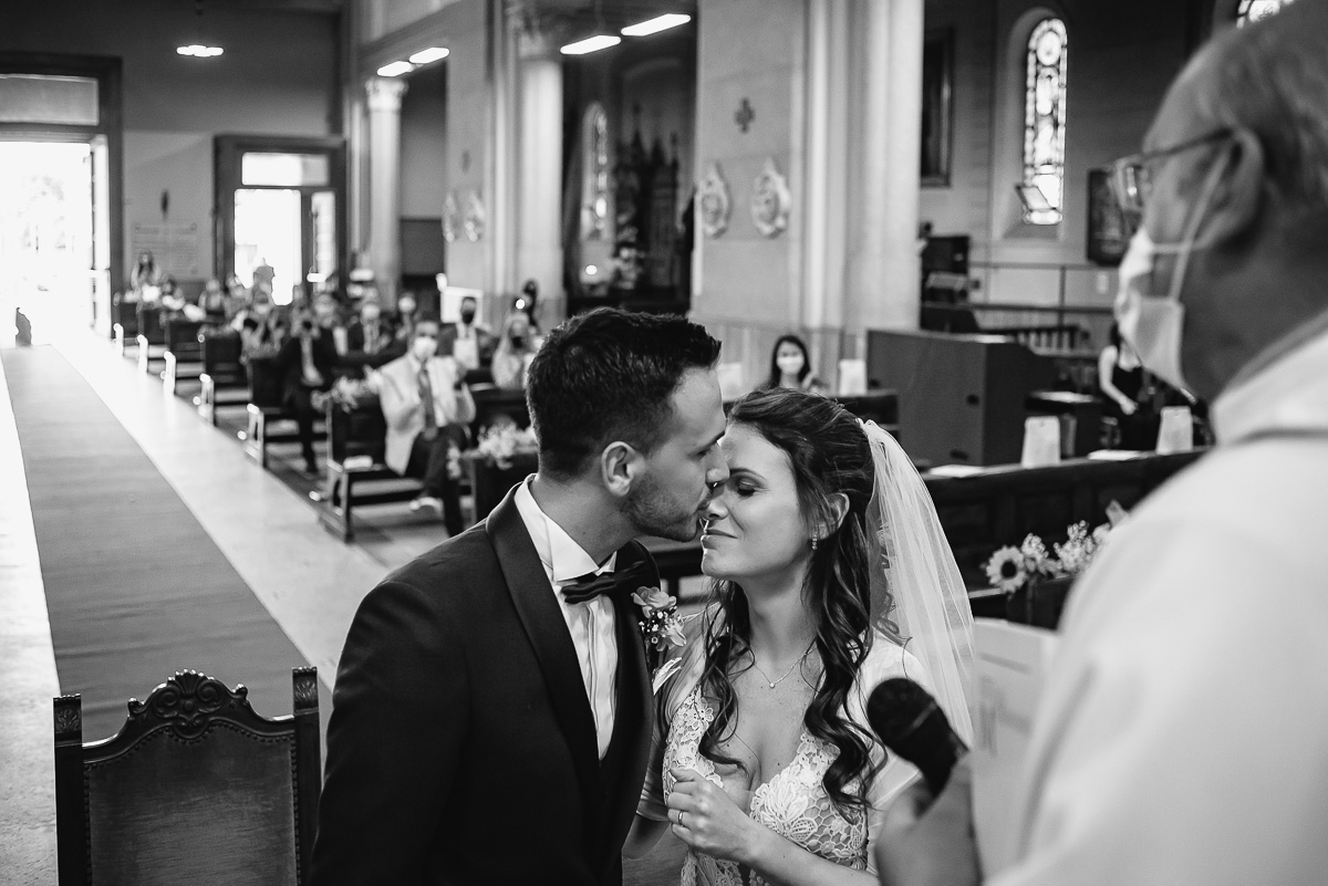 Matrimonio a Torino. Cerimonia nella chiesa Patrocinio San Giuseppe.Sposo bacia la sposa sulla fronte. Bianco e nero.