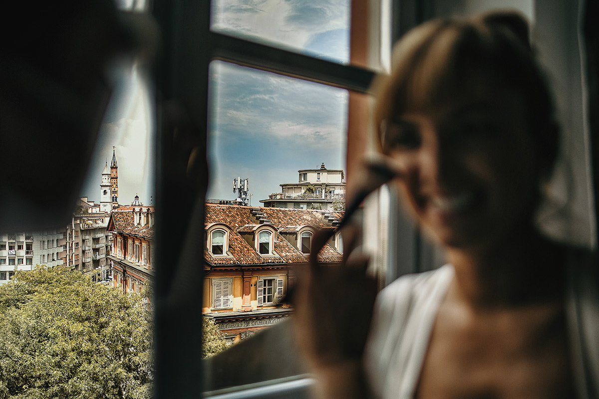 Matrimonio a Torino in un palazzo storico di Piazza Statuto. Preparazione della sposa. trucco alla finestra con scorcio di Torino.