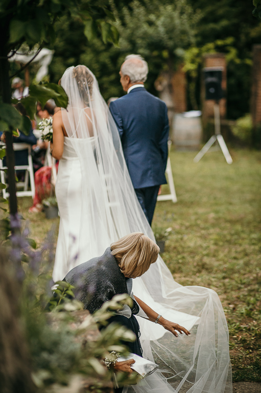 Matrimonio a Villa Delfini di Morsasco (AL) nel Monferrato. Cerimonia. sposa va verso l'altare al braccio del padre. mamma sistema il velo.