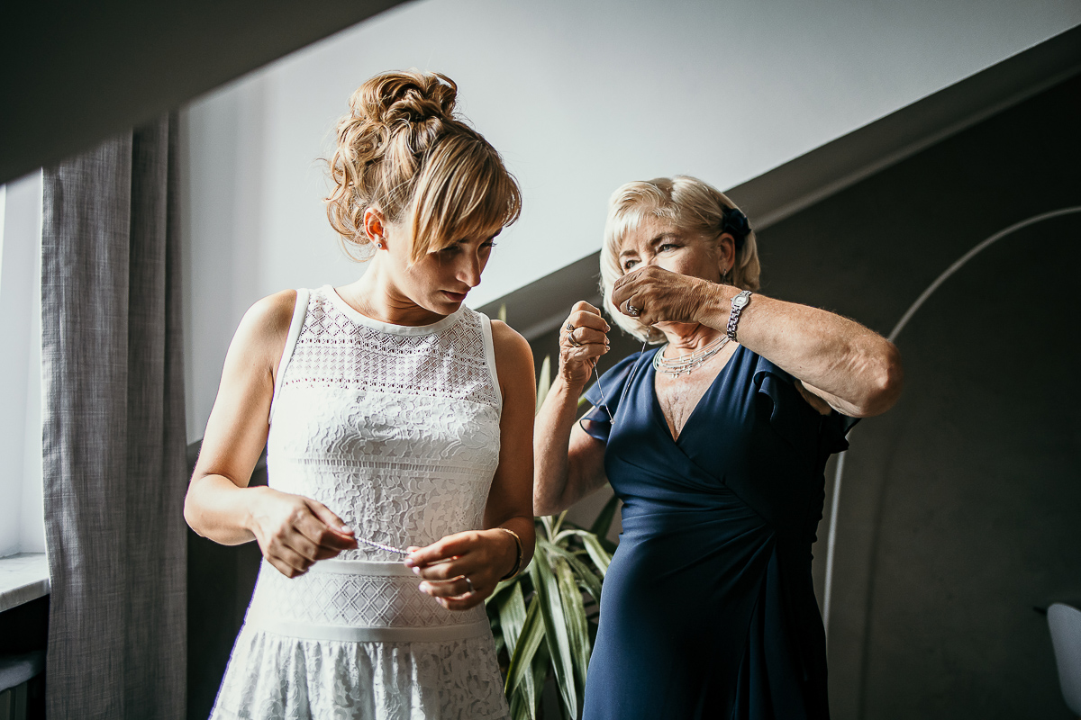 Matrimonio a Torino in un palazzo storico di Piazza Statuto. Preparazione della sposa. mamma metta una collana alla sposa.