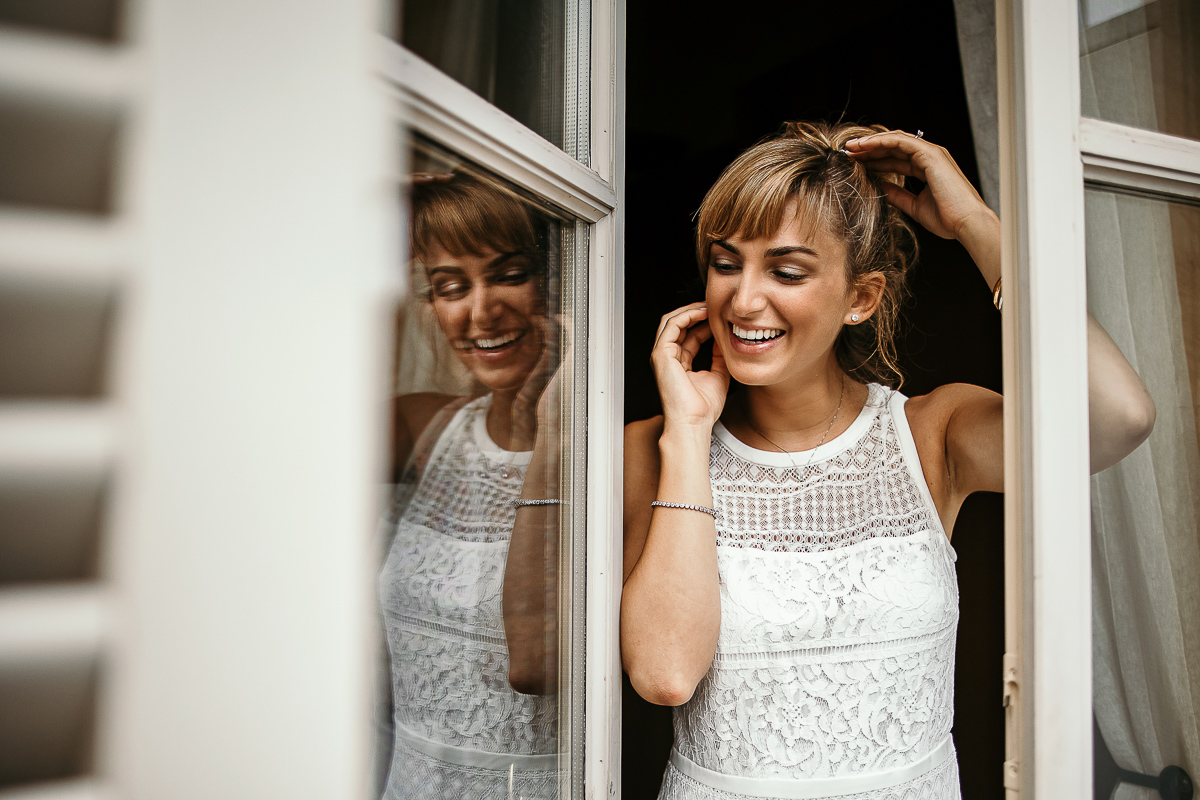 Matrimonio a Torino in un palazzo storico di Piazza Statuto. Preparazione della sposa. Ritratto della sposa sorridente riflessa.