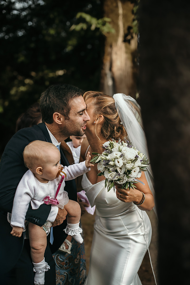 Matrimonio a Villa Delfini di Morsasco (AL) nel Monferrato. Cerimonia.. baci e abbracci. Bimba cerca di prendere i fiori del bouquet della sposa.