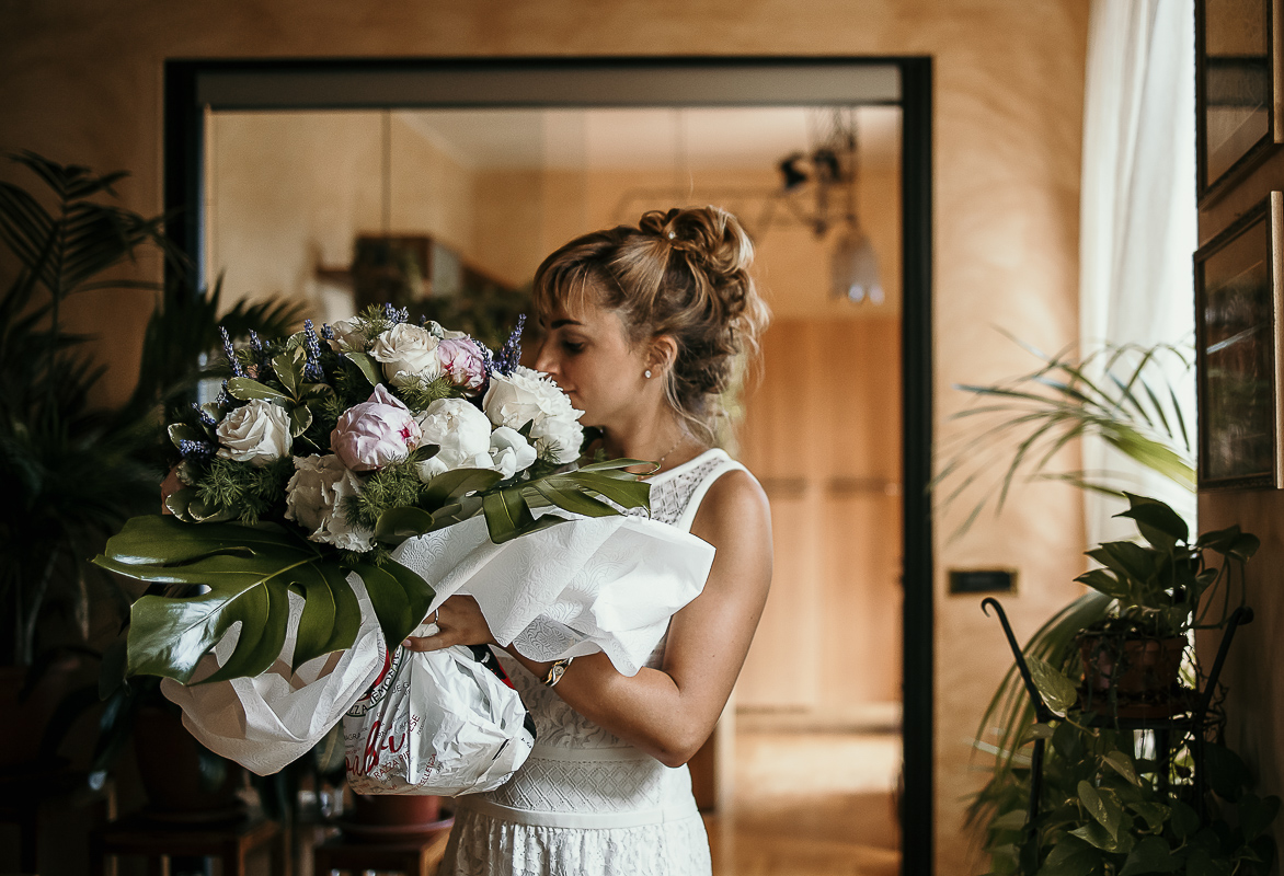 Matrimonio a Torino in un palazzo storico di Piazza Statuto. Preparazione della sposa. Sposa con il viso immerso in un mazzo di fiori.