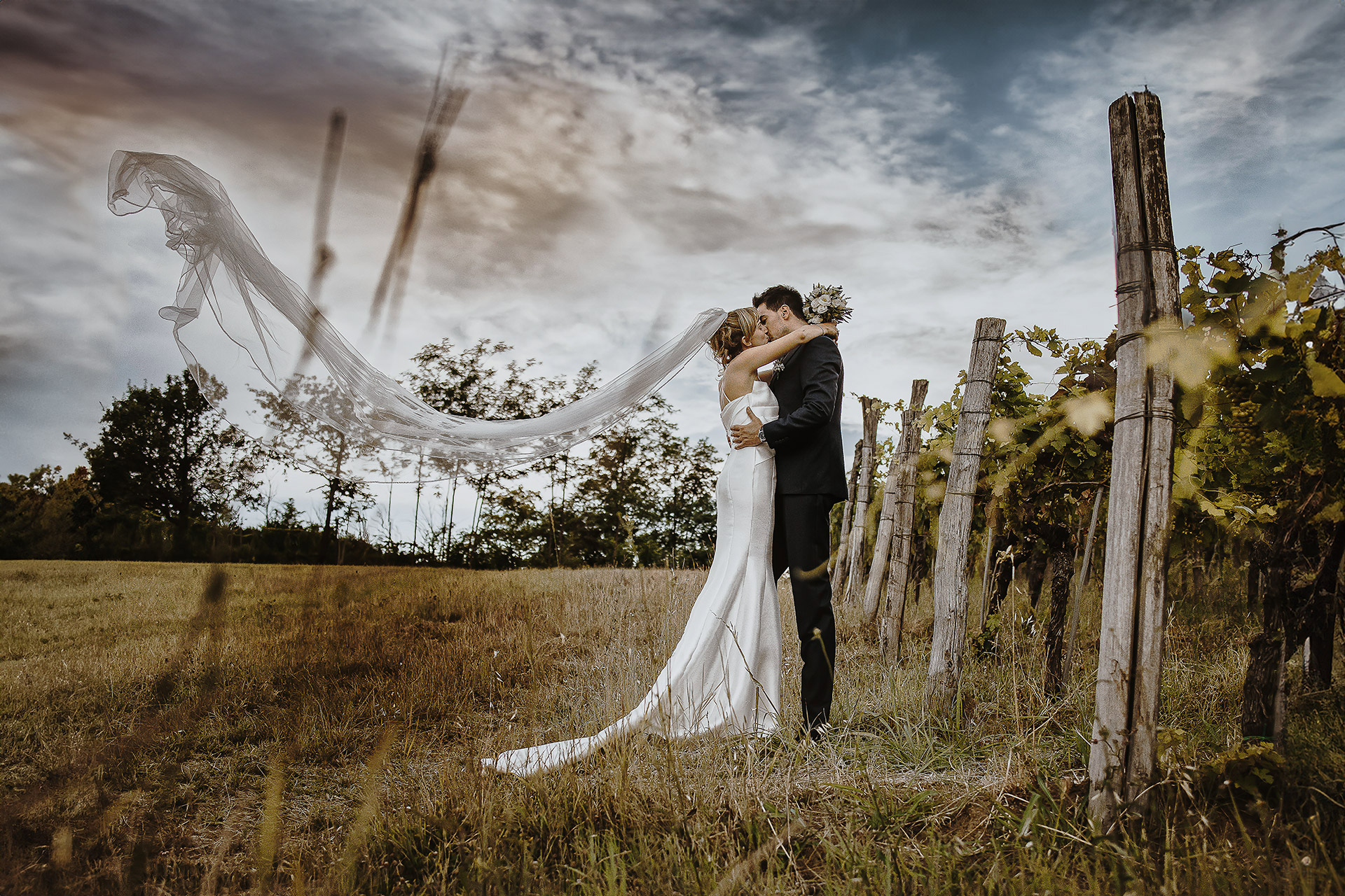 Villa Delfini di Morsasco (AL). Luxury wedding di Cristina ed Andrea. Sessione di coppia tra i vigneti. Bacio. Velo che viene fatto volare.