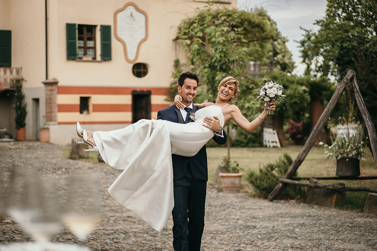Matrimonio a Villa Delfini di Morsasco (AL) nel Monferrato. Aperitivo. Sposo porta in braccio la sposa.