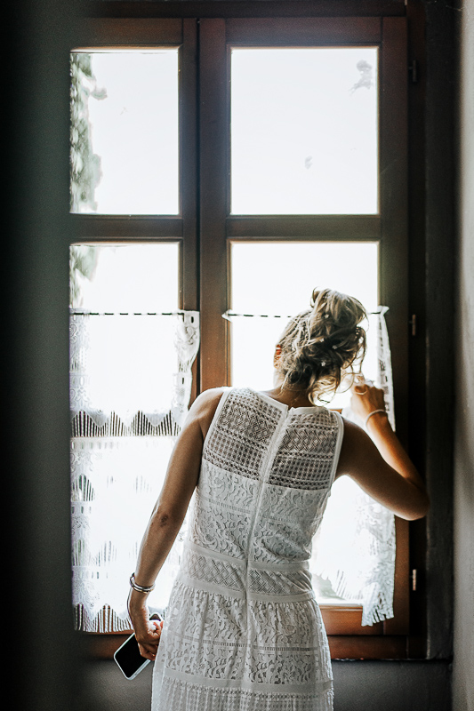 Matrimonio a Villa Delfini di Morsasco (AL) nel Monferrato. Preparazione dell a sposa. Sposa guarda alla finestra l'arrivo delle altre damigelle.