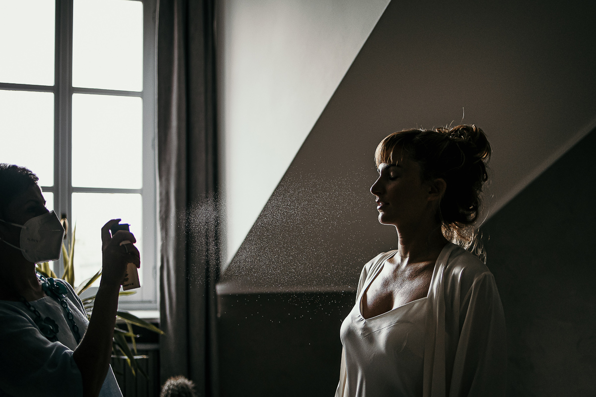 Matrimonio a Torino in un palazzo storico di Piazza Statuto. Preparazione della sposa. Spruzzo del fissativo in controluce.