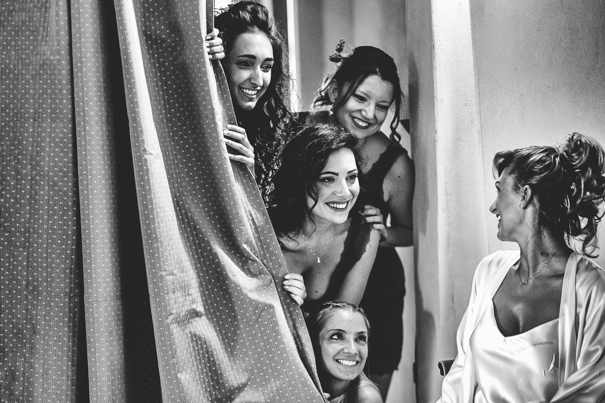 Matrimonio a Villa Delfini di Morsasco (AL) nel Monferrato. Preparazione dell a sposa. Damigelle guardano la sposa da una tenda.