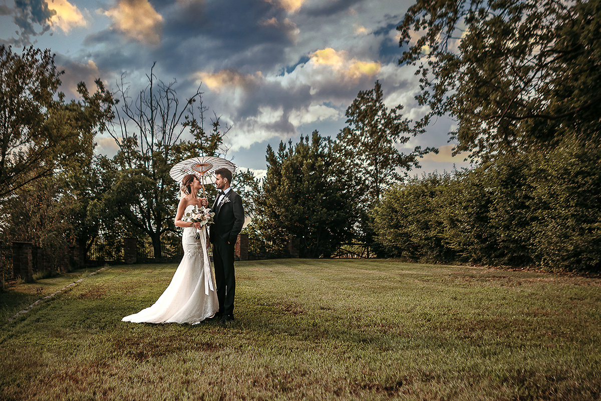 Matrimonio a Villa Fiorita ad Asti. Servizio di coppia.Sposa con ombrellino cinese. cielo con colori stupendi