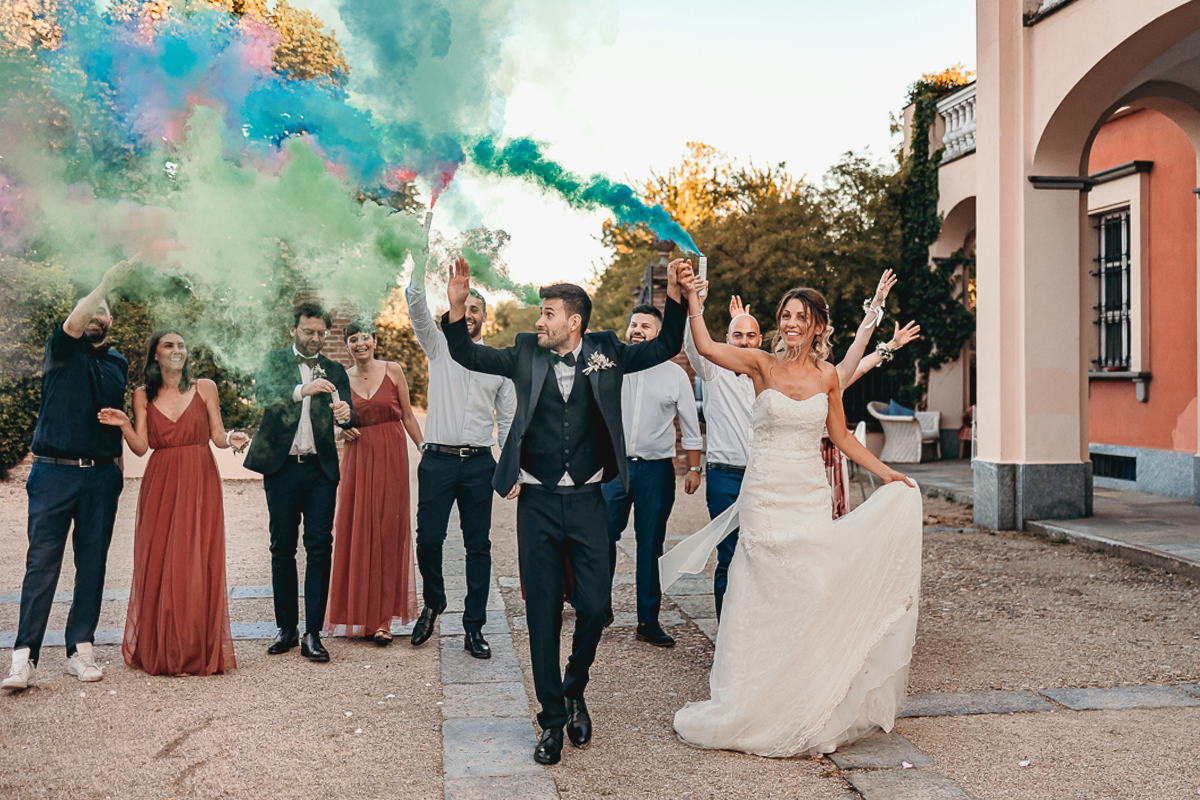 Matrimonio a Villa Fiorita ad Asti. Ricevimento. Sposi con gli amici ed i fumogeni colorati.