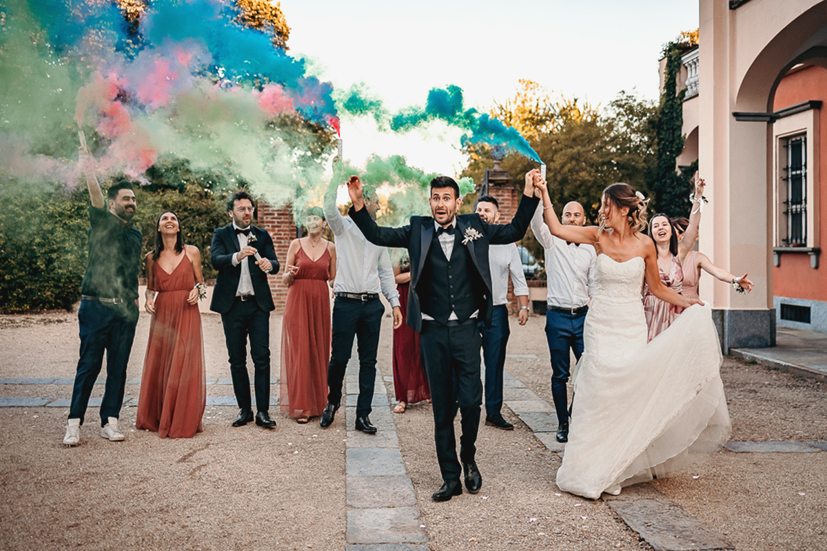 Matrimonio a Villa Fiorita ad Asti. Ricevimento. Sposi con gli amici ed i fumogeni colorati.