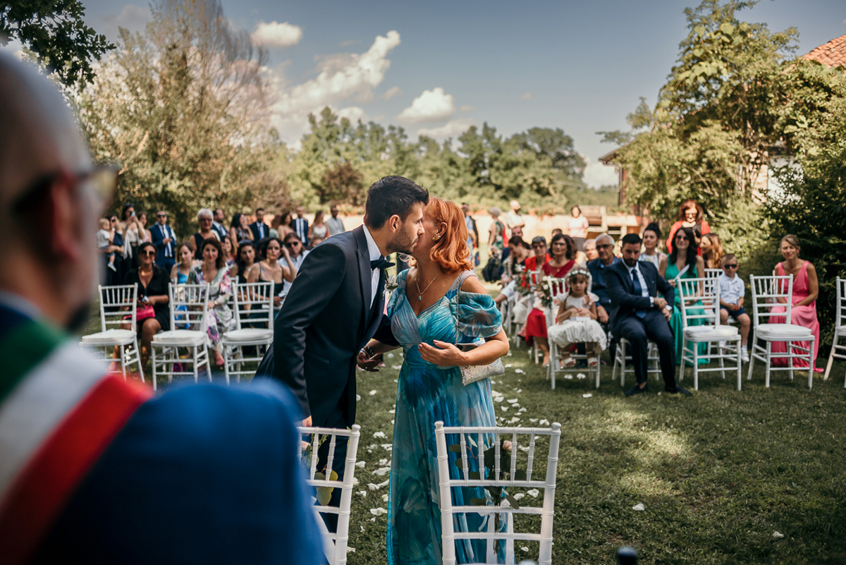 Matrimonio a Villa Fiorita ad Asti. Cerimonia.Sposo che bacia la madre davanti al sindaco
