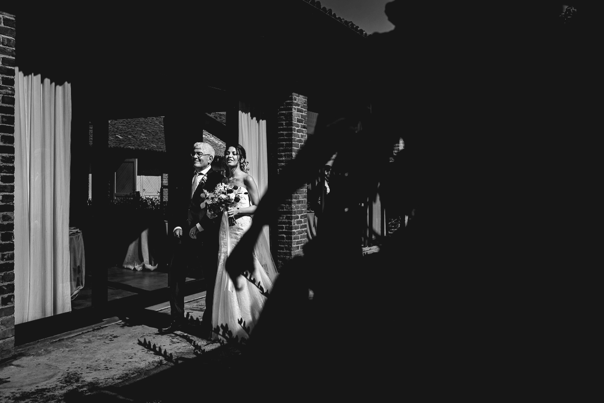 Matrimonio a Villa Fiorita ad Asti. Cerimonia.Sposa che sta per entrare con il padre. Bianco e nero.