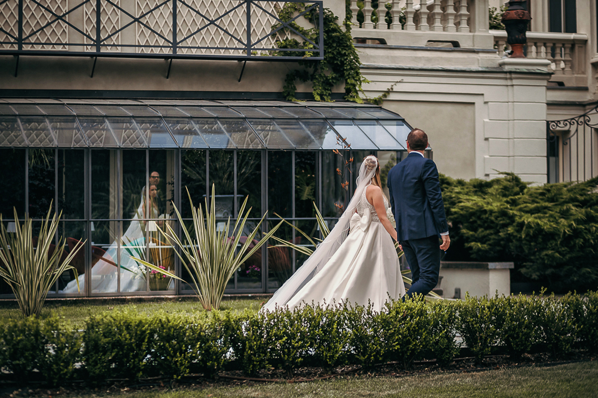 Villa Sassi matrimonio di Giulia e Nicolò. Ritratto degli sposi. Sposi vanno verso l'aperitivo. Riflessi nelle vetrate della villa.