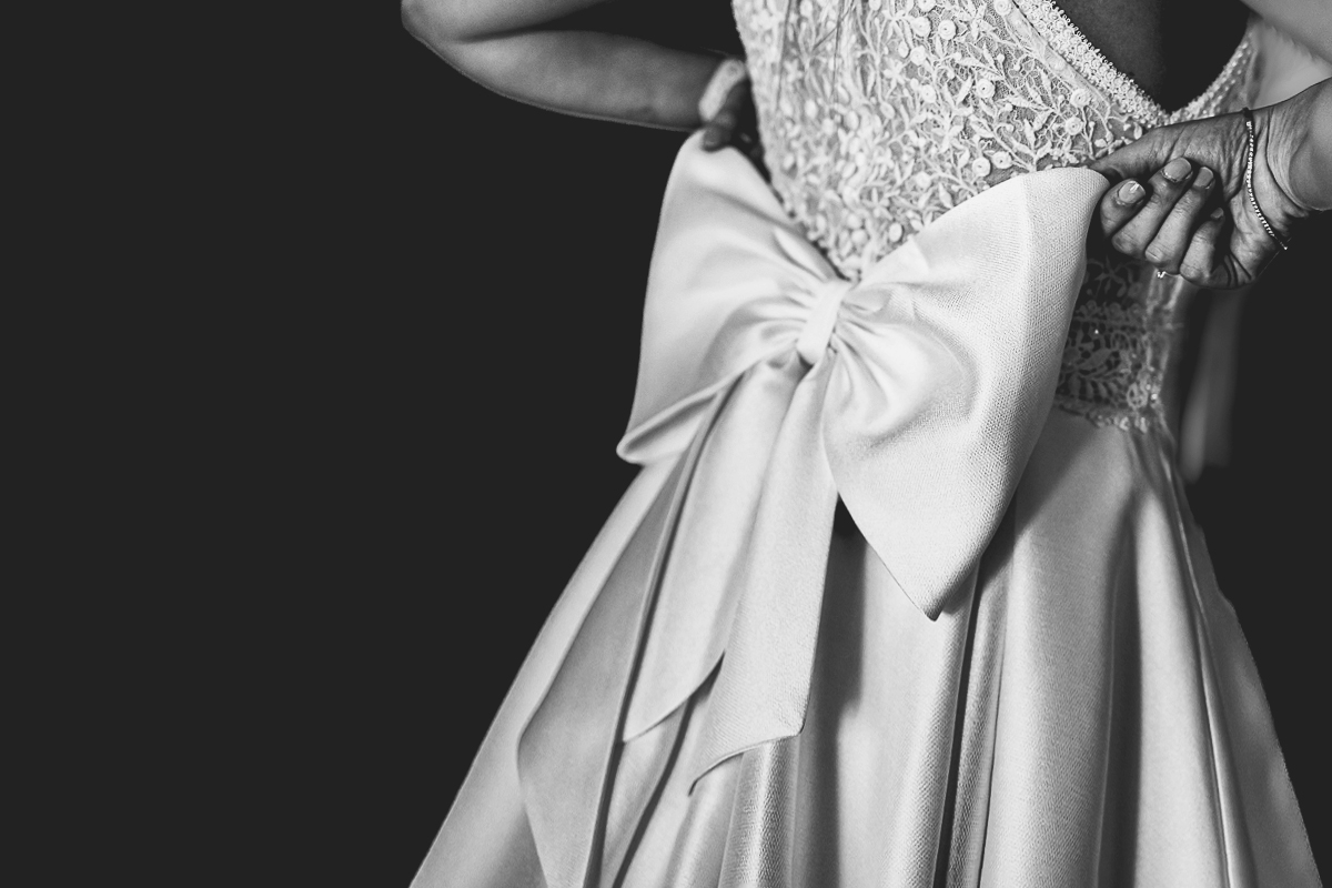 Matrimonio a Villa Sassi. Preparazione della sposa a Chieri. Dettaglio sul grande fiocco dietro l'abito della sposa.