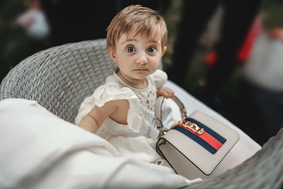 Villa Sassi matrimonio di Giulia e Nicolò. Aperitivo. Bambina piccola degli sposi seduta con la borsetta di Gucci della nonna.