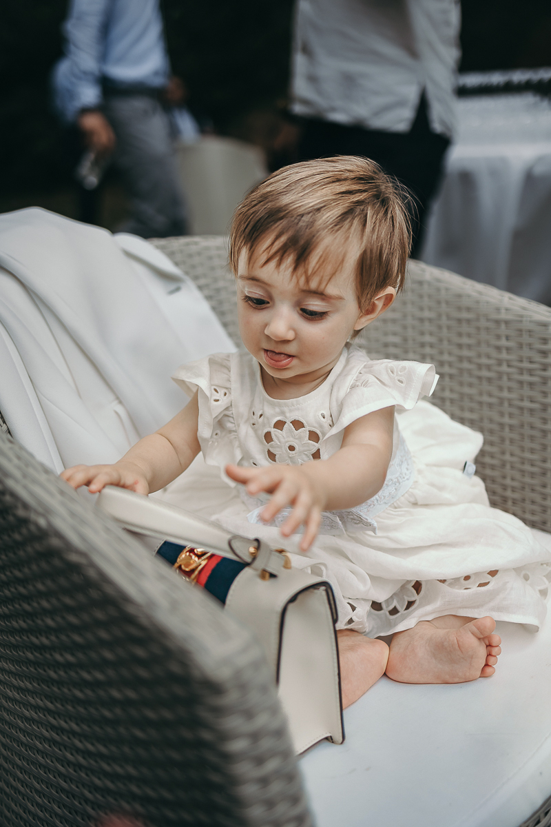 Villa Sassi matrimonio di Giulia e Nicolò. Aperitivo. Bambina piccola degli sposi seduta con la borsetta di Gucci della nonna.