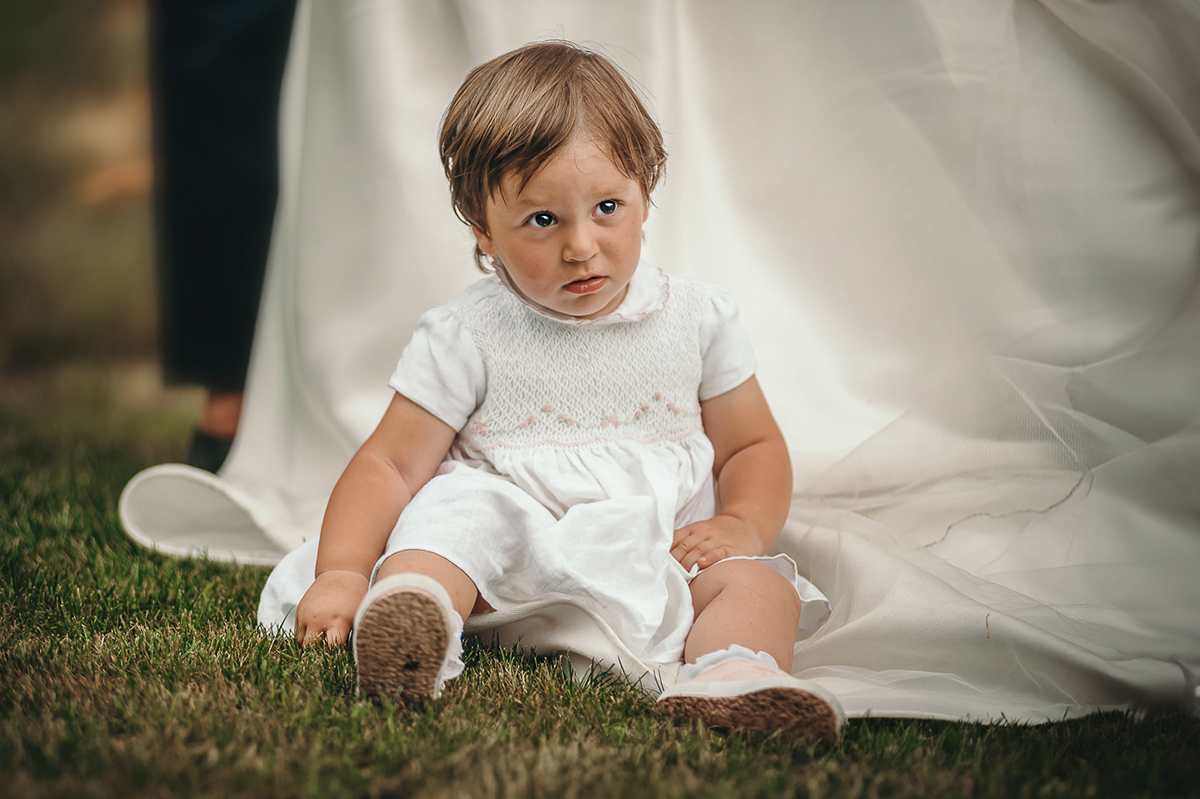 Villa Sassi matrimonio di Giulia e Nicolò. Aperitivo.Bambina seduta sull'abito della sposa, primo piano.