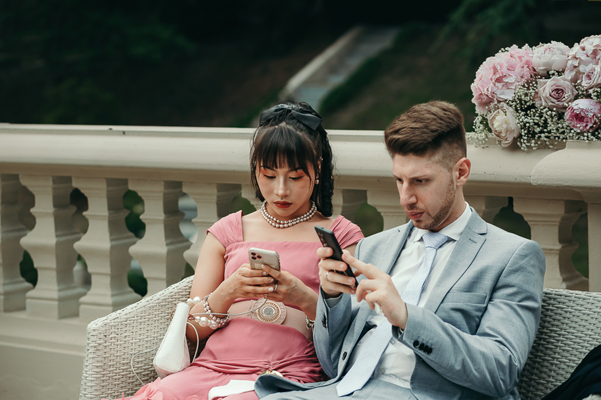 Villa Sassi matrimonio di Giulia e Nicolò. Aperitivo. coppia di invitati intenti a scrivere sul cellulare.