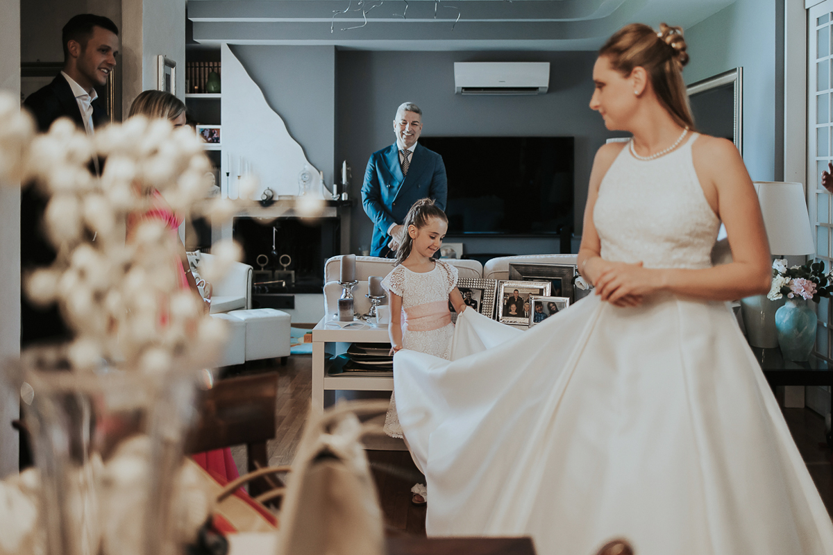 Matrimonio a Villa Sassi. Preparazione della sposa a Chieri. Sposa nel salone in mezzo ai parenti. Bambina tiene il suo vestito.