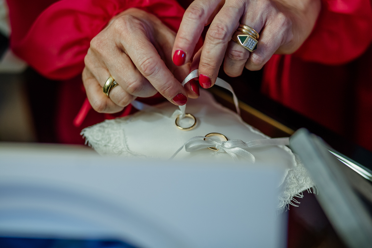 Matrimonio a Villa Sassi. Preparazione della sposa a Chieri. mamma della sposa lega gli anelli al cucino portafedi.