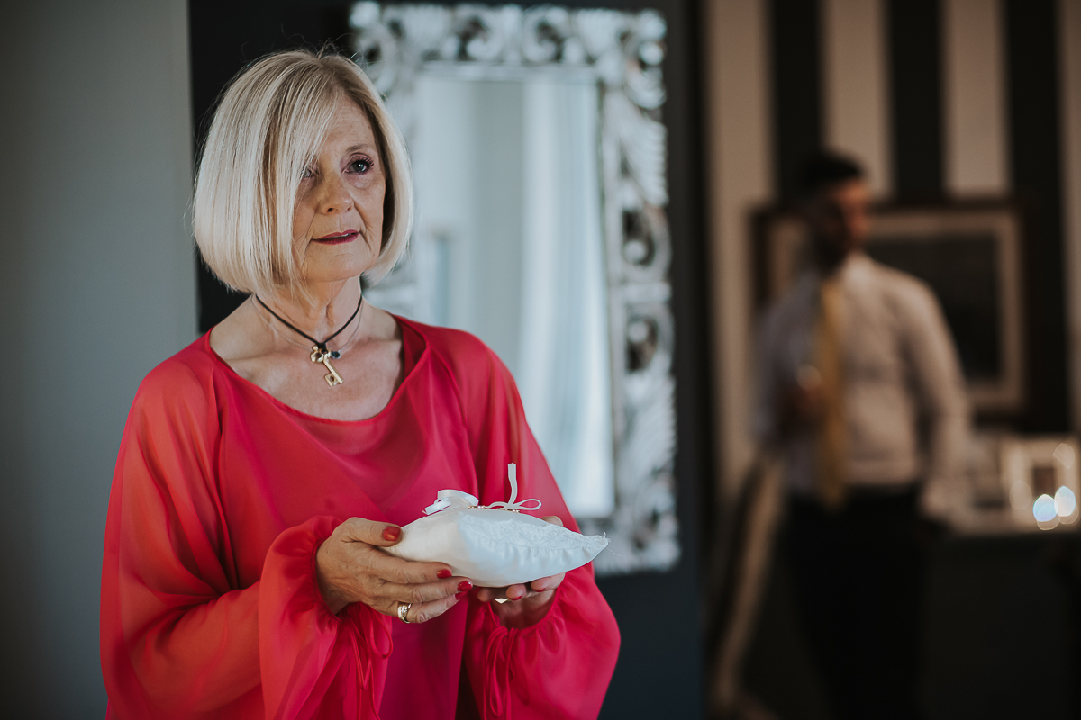 Matrimonio a Villa Sassi. Preparazione della sposa a Chieri. mamma della sposa tiene in mano il cuscino portafedi.