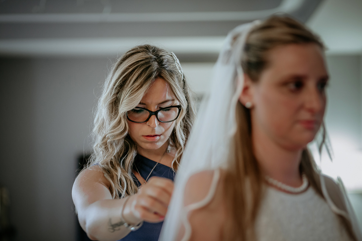Matrimonio a Villa Sassi. Preparazione della sposa a Chieri. Amica mette il velo alla sposa.