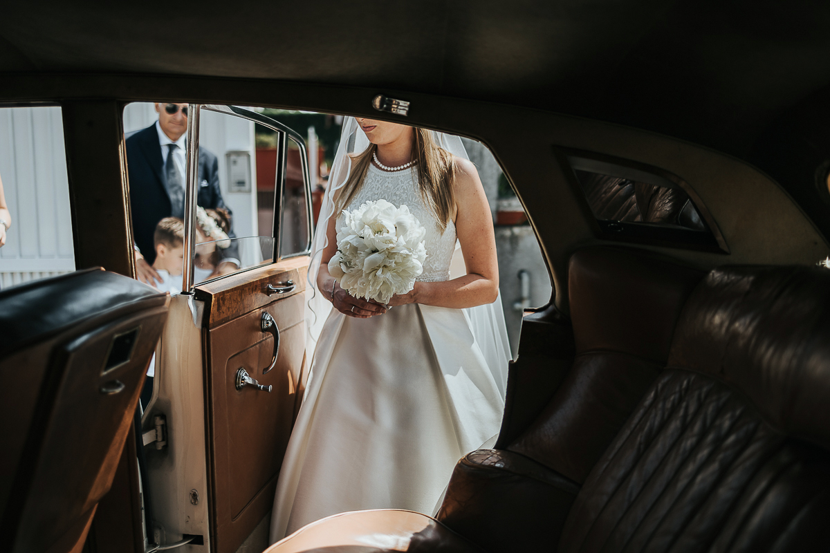 Matrimonio a Villa Sassi. Preparazione della sposa a Chieri. Auto d'epoca bianca. Sposa entra in auto.