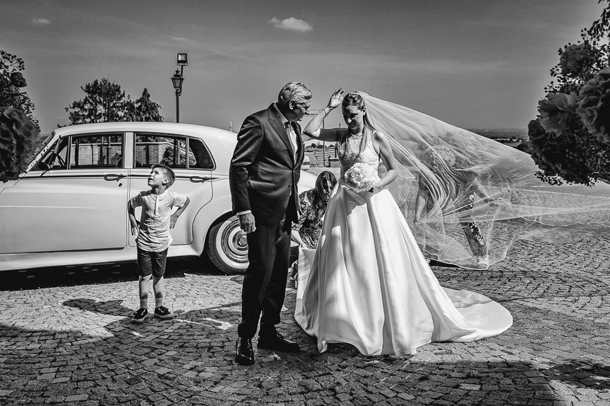 Villa Sassi matrimonio di Giulia e Nicolò. Cerimonia nella chiesa di santa Maria della Spina a Baldissero Torinese. Sposa esce dall'auto d'epoca bianca. Con il padre e il paggetto.