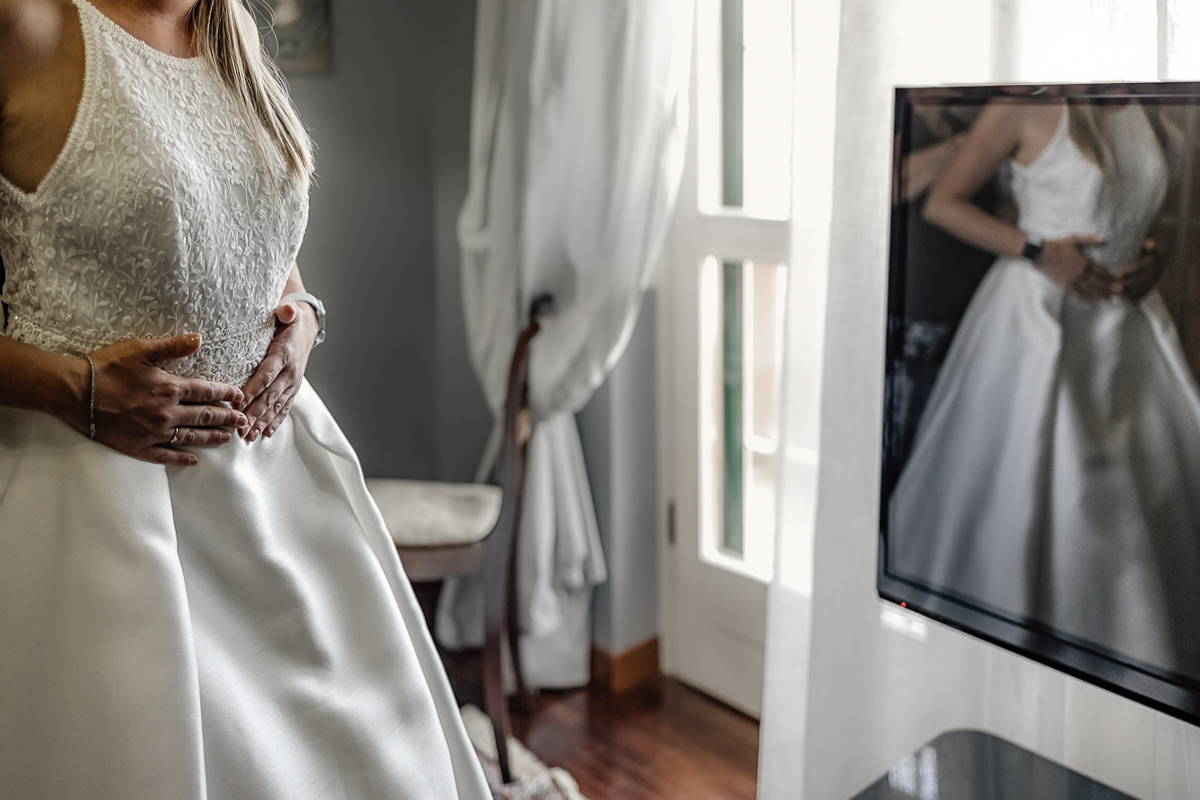 Matrimonio a Villa Sassi. Preparazione della sposa a Chieri. Sposa riflessa nel televisore.