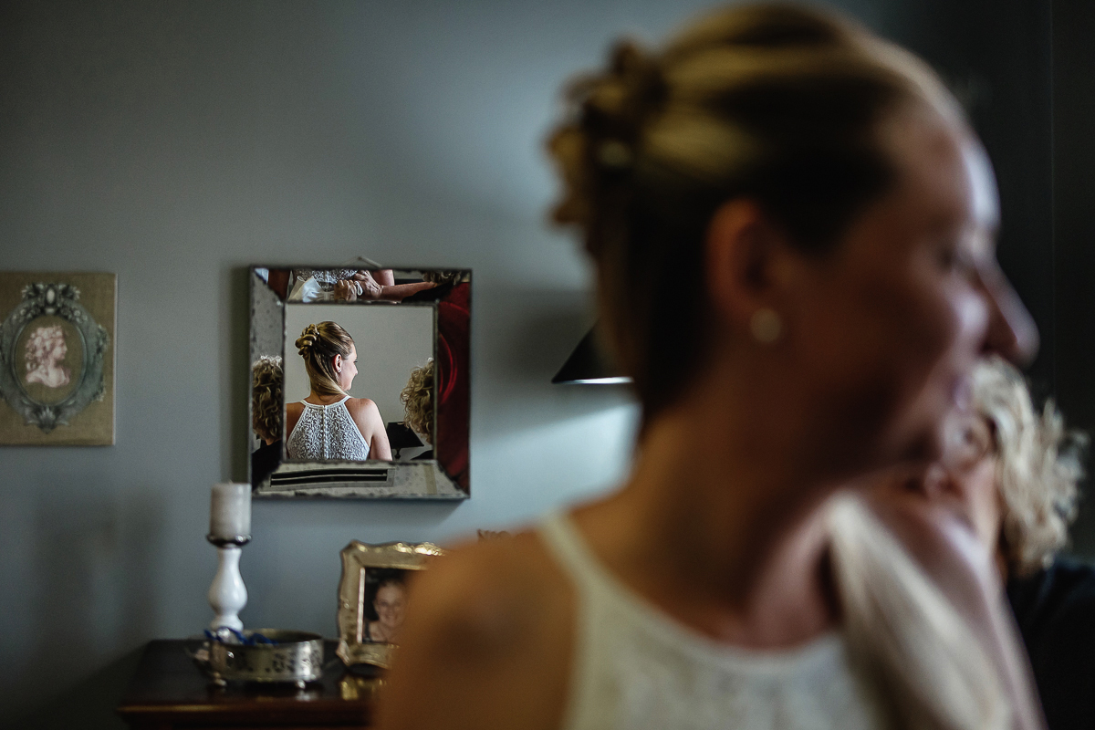 Matrimonio a Villa Sassi. Preparazione della sposa a Chieri. Schiena e acconciatura della sposa riflesse nello specchio.