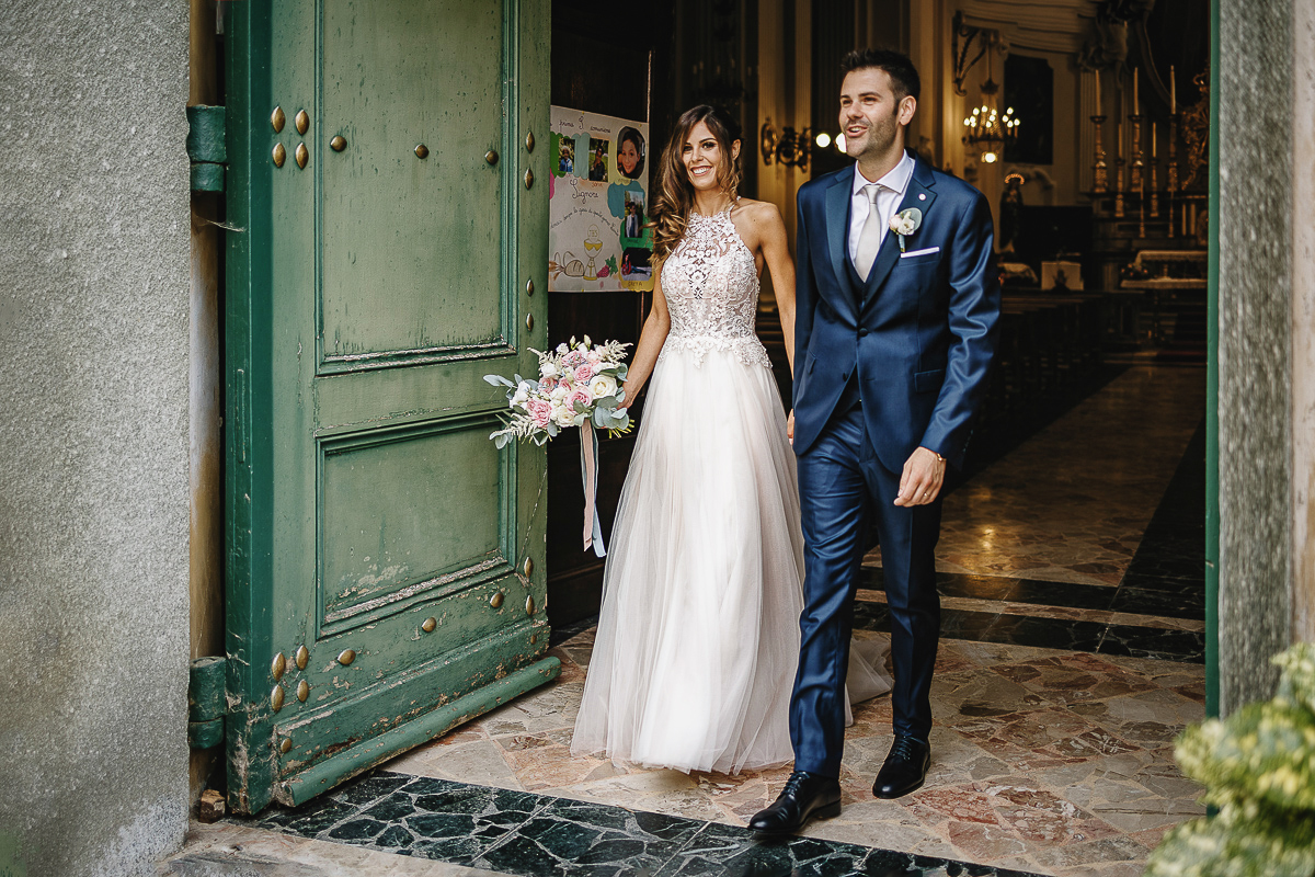 Matrimonio nella chiesa parrochiale di Arignano. Cerimonia.Sposi in uscita sulla soglia del portone della chiesa.