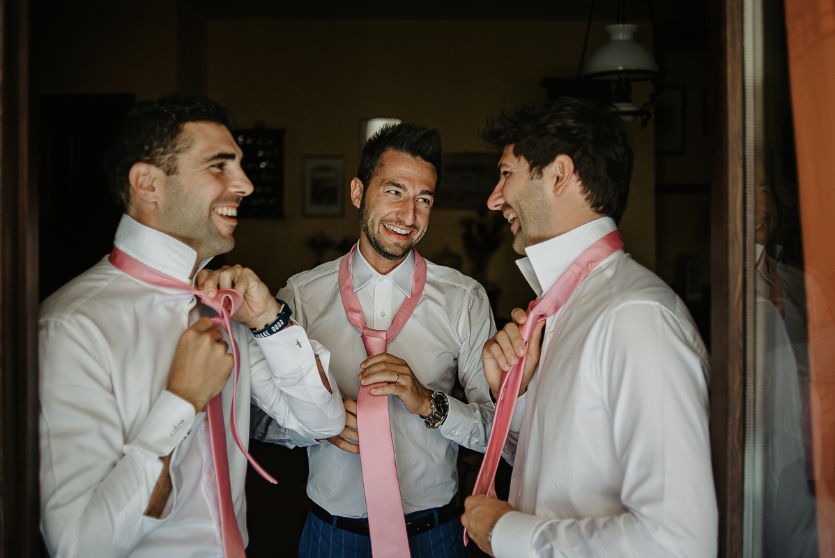 Matrimonio ad Arignano. Preparazione dello sposo.Amici e testimoni dello sposo si annodano le cravatte.