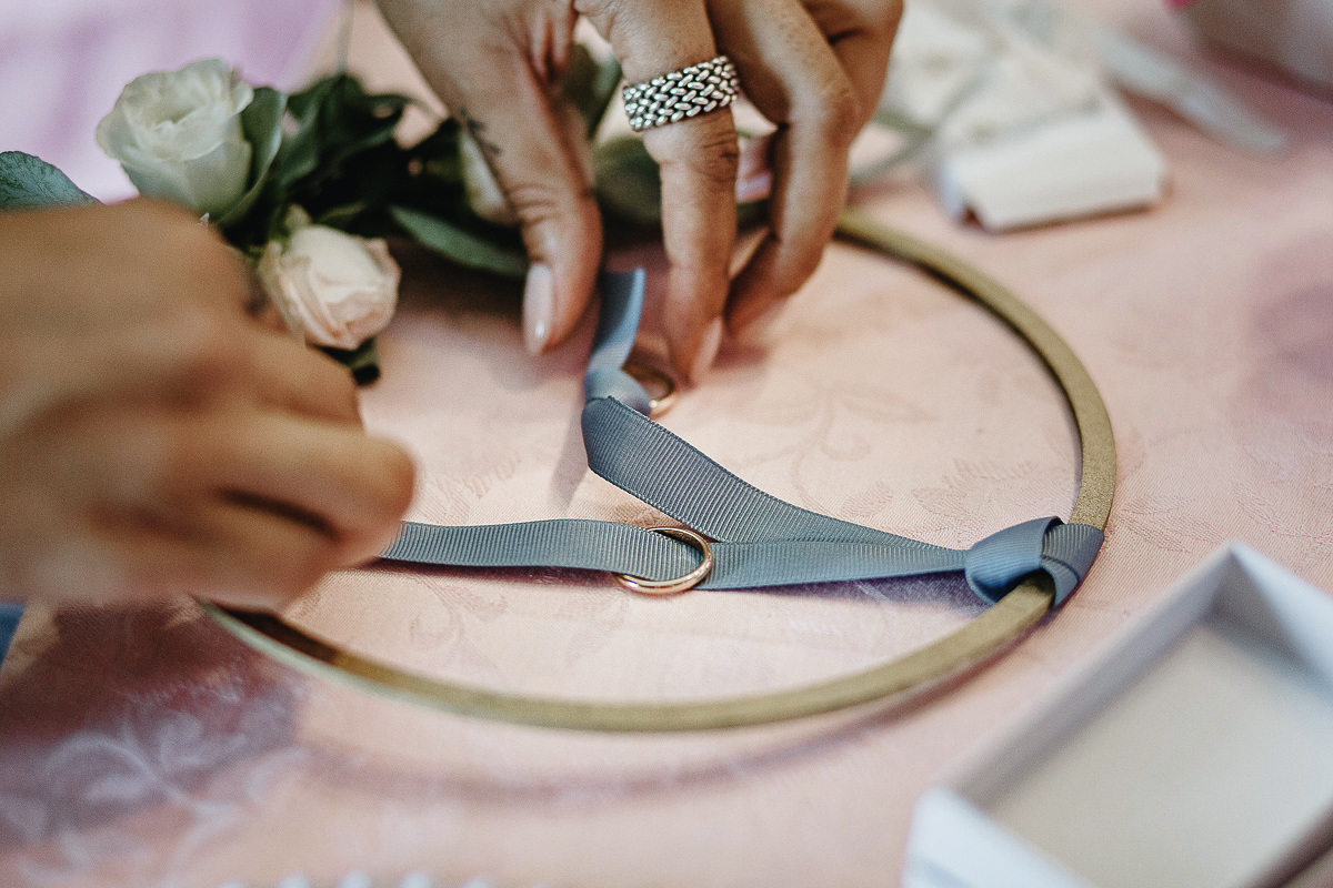 Matrimonio ad Arignano. Preparazione della sposa. Testimone sistema gli anelli sul portaanelli.