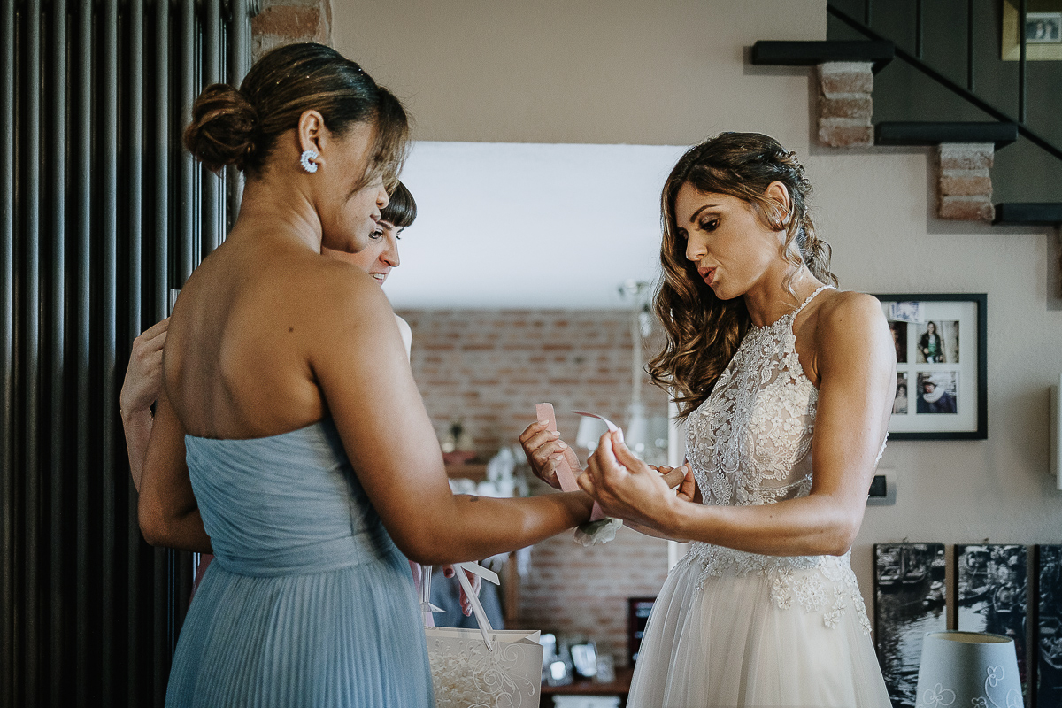 Matrimonio ad Arignano. Preparazione della sposa. Sposa mette il corsage ad ua delle damigelle.