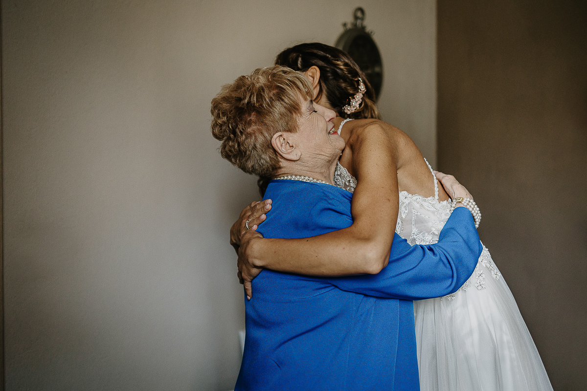 Matrimonio ad Arignano. Preparazione della sposa. Sposa abbraccia la nonna.