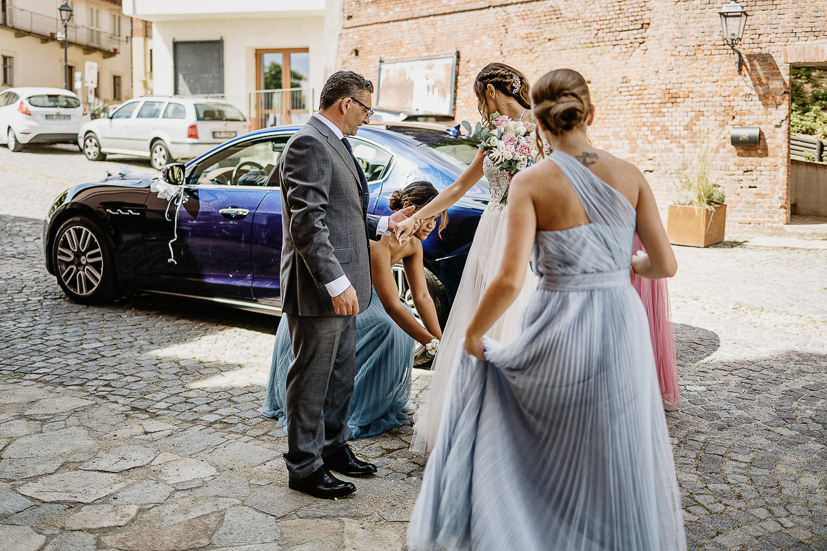 Matrimonio nella chiesa parrochiale di Arignano. Cerimonia. Sposa prima di entrare in chiesa. Damigella che le sistema l'abito.