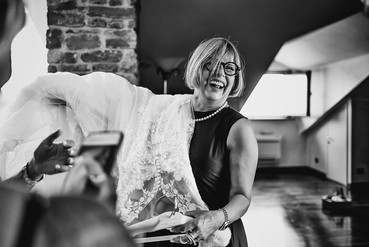 Castello dei Solaro, matrimonio di Noemi e Pietro. Preparazione della sposa. mamma sorridente porta l'abito della sposa.
