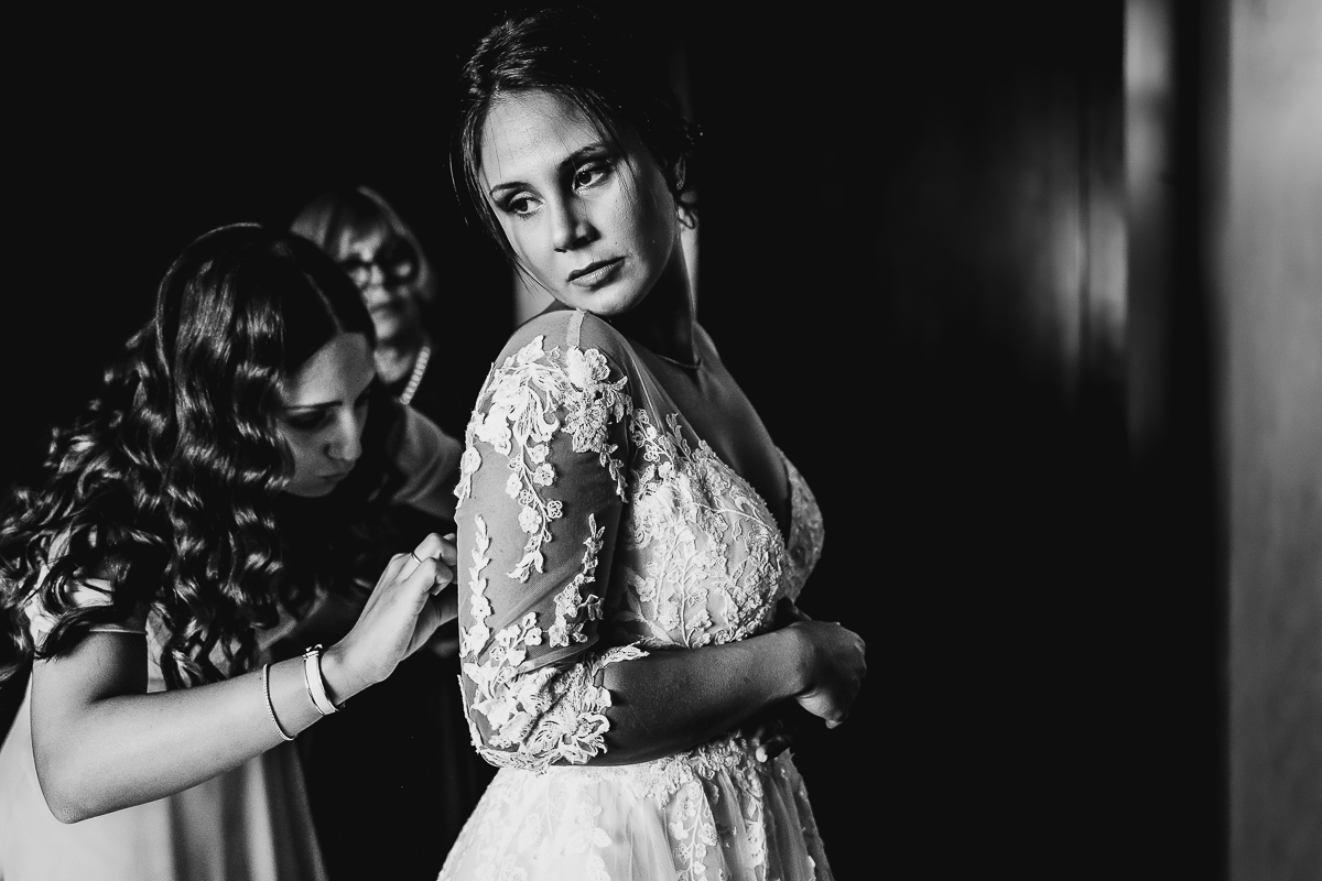 Castello dei Solaro, matrimonio di Noemi e Pietro. Preparazione della sposa. Sorella abbottona l'abito della sposa.