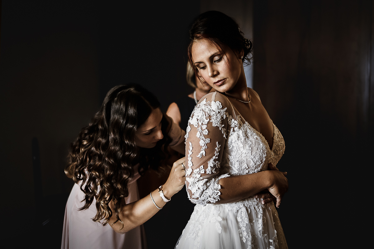 Castello dei Solaro, matrimonio di Noemi e Pietro. Preparazione della sposa. Sorella abbottona l'abito della sposa.