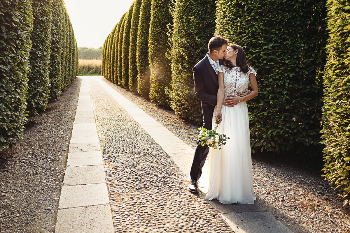 Tenuta La Cascinetta di Buriasco. Matrimonio. Sessione di coppia al tramonto lungo il viale di cipressi. Bacio