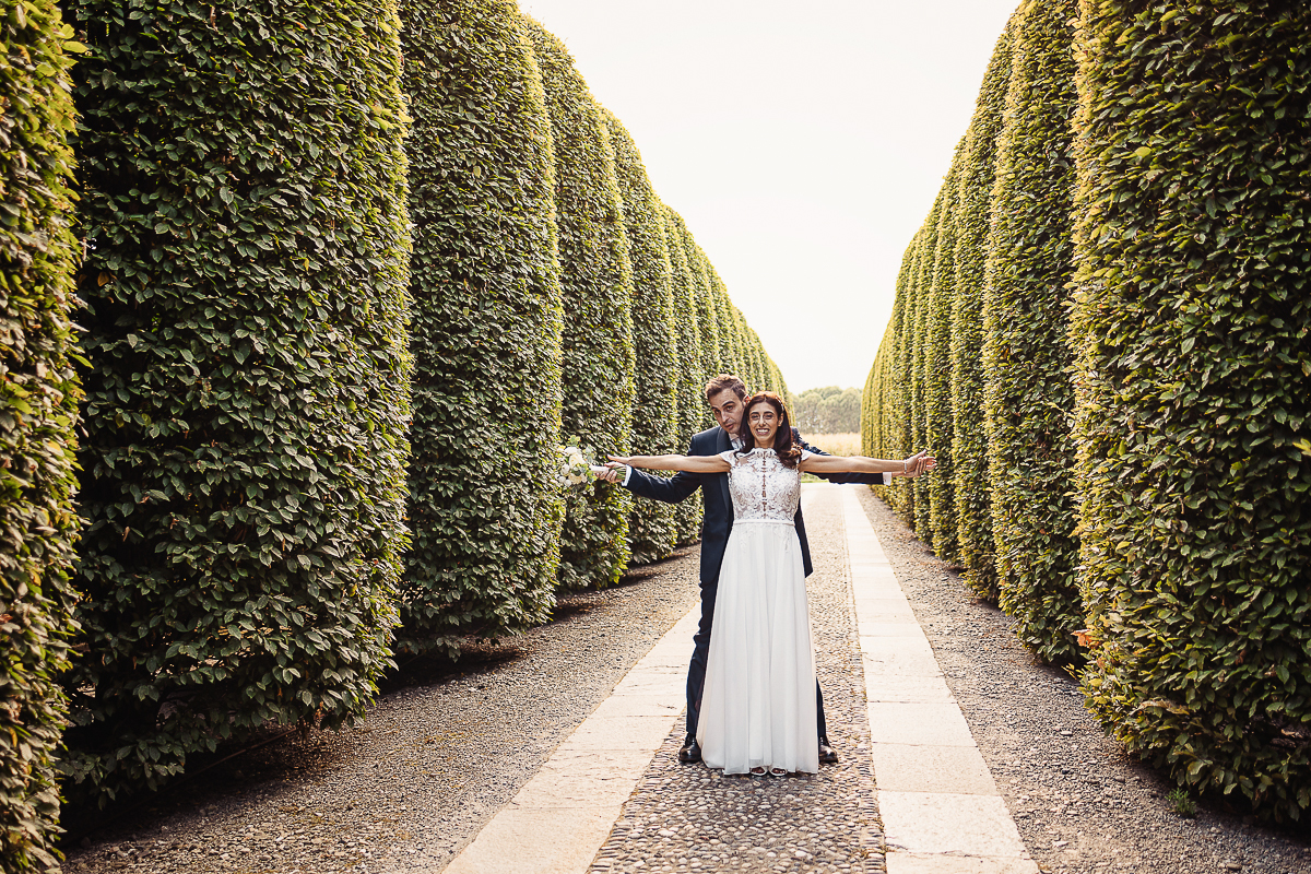 Tenuta La Cascinetta di Buriasco. Matrimonio. Sessione di coppia al tramonto lungo il viale di cipressi. Sposi imitano la scena finale del Titanic.