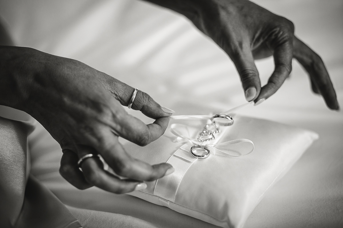 Tenuta La Cascinetta di Buriasco. Matrimonio. Preparazione della sposa. Sposa che lega le fedi al cuscinetto portafedi.
