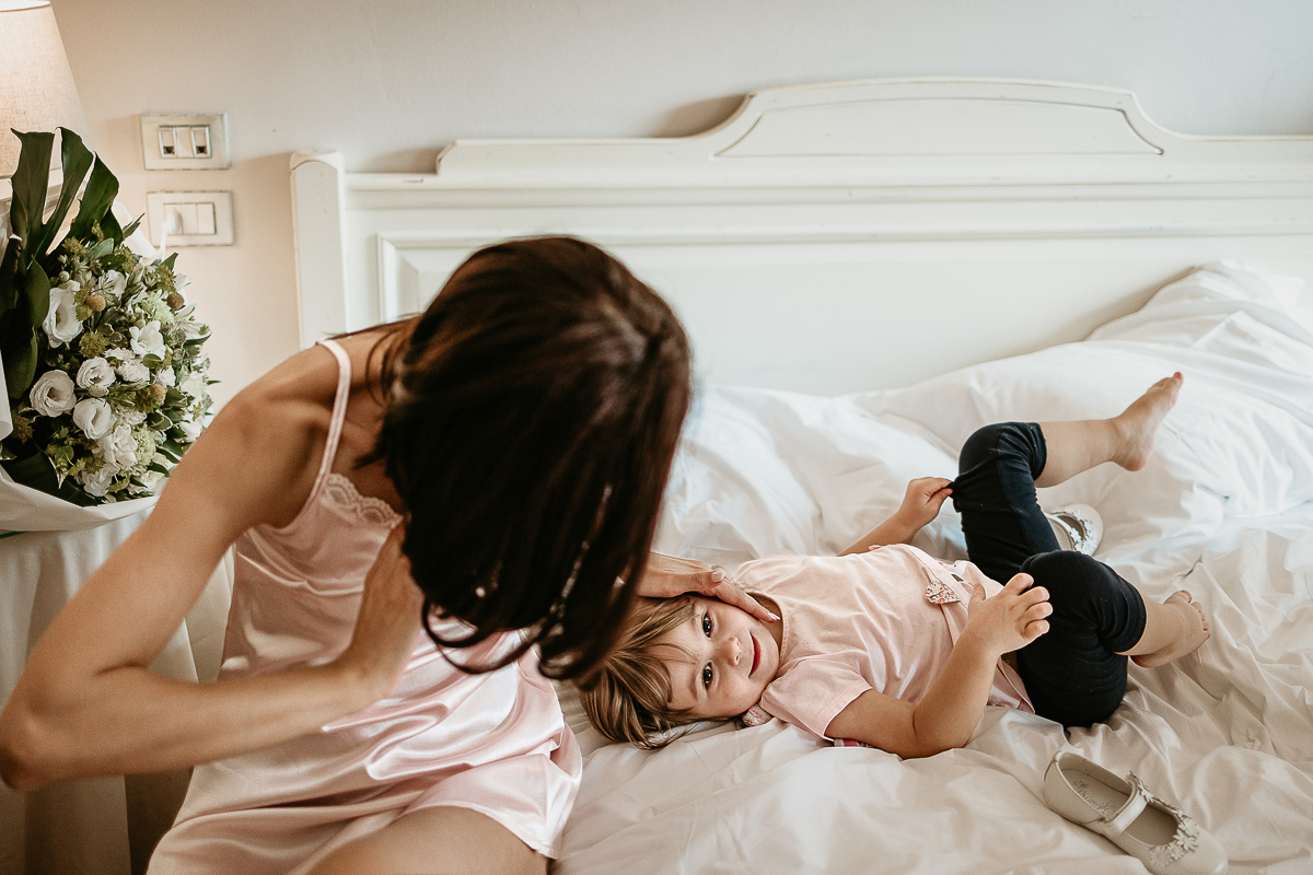 Tenuta La Cascinetta di Buriasco. Matrimonio. Preparazione della sposa. sposa con la sua bambina sul letto.