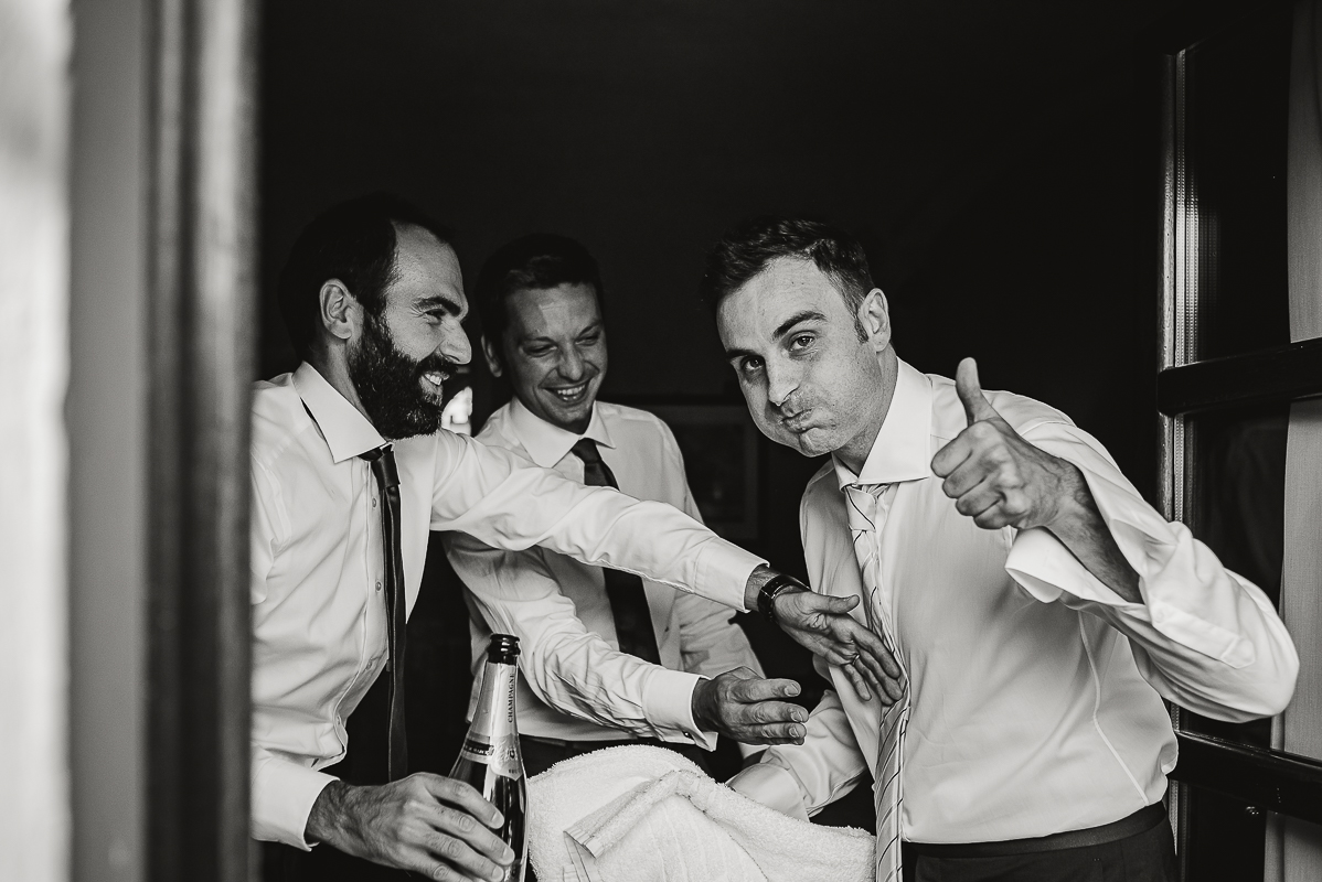 Tenuta La Cascinetta di Buriasco. Matrimonio. Preparazione dello sposo. Sposo dopo aver bevuto lo spumante dalla bottiglia. Ha la bocca piena e il viso spruzzato.