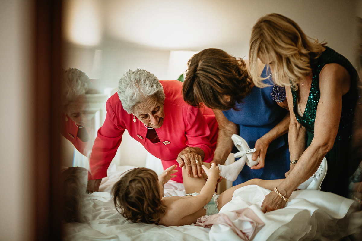 Tenuta La Cascinetta di Buriasco. Matrimonio. Preparazione della sposa. Le nonne e la bisnonna vestono la bambina degli sposi.