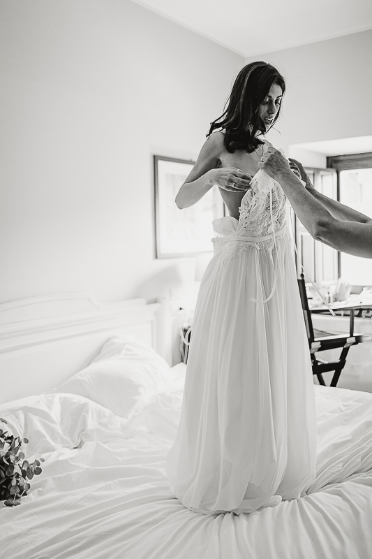 Tenuta La Cascinetta di Buriasco. Matrimonio. Preparazione della sposa. Mamma veste la sposa sul letto,