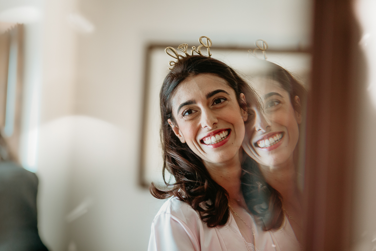 Tenuta La Cascinetta di Buriasco. Matrimonio. Preparazione della sposa. Ritratto della sposa allo specchio con cerchietto Bride